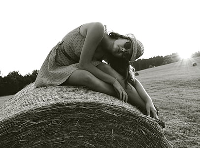 grayscale photography of woman sitting on hay