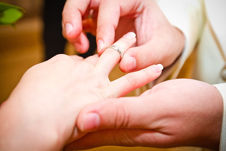 candid photography of man's hand wearing bridal ring on woman's finger