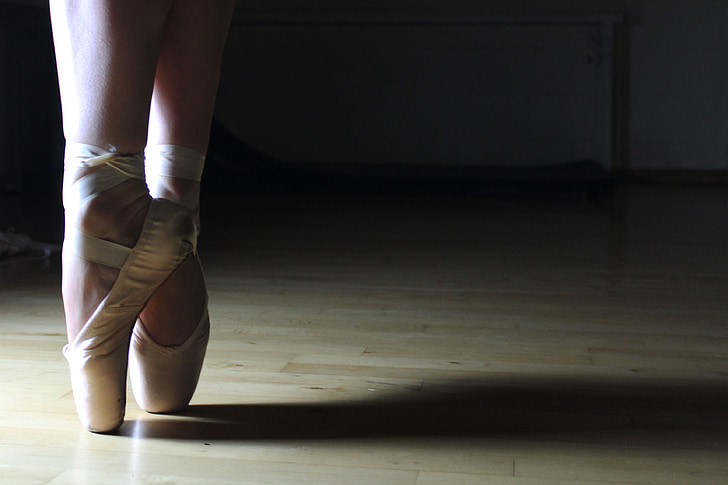 person wearing white ballet shoes doing ballet dance