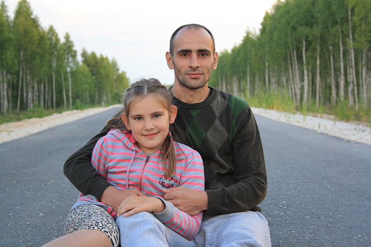 man and girl sitting in the middle of the road
