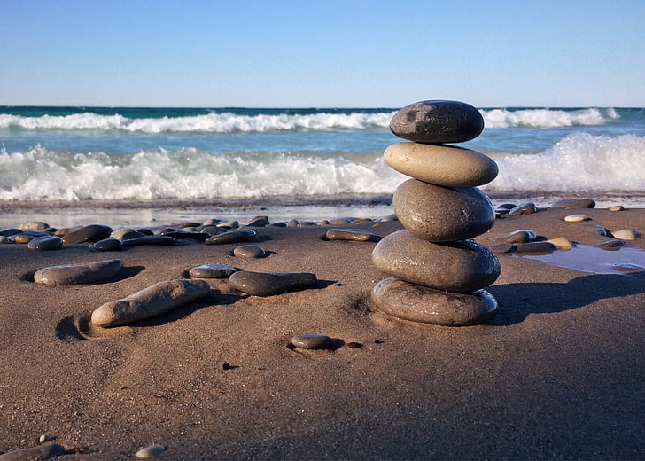 photo of five stacked stones on the beach
