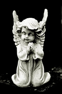 cherub praying figurine on top of black surface
