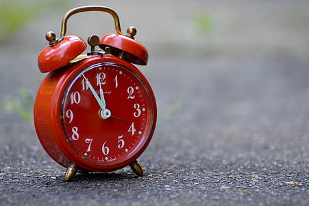 selective focus photography of red twin-bell alarm clock on pavement