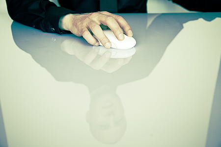 person holding white cordless computer mouse on white table