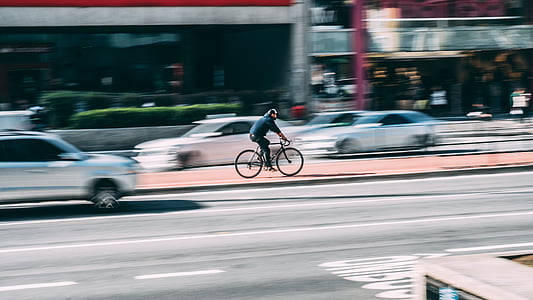 selective focus photo of person riding on bicycle beside road