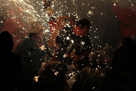 man standing surrounded with people lighting sparklers