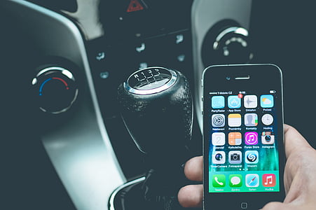person holding a black iPhone 4 while inside a car