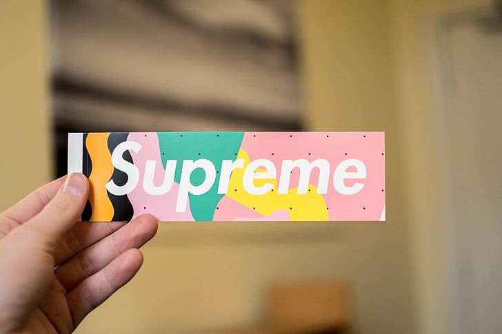 person holding multicolored Supreme sticker