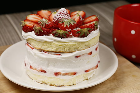 round strawberry cake beside mug