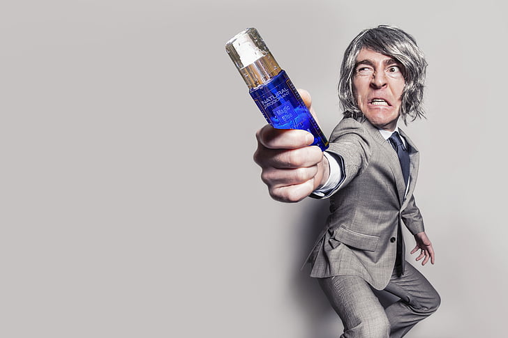 man in gray label suit jacket holding blue fragrance bottle