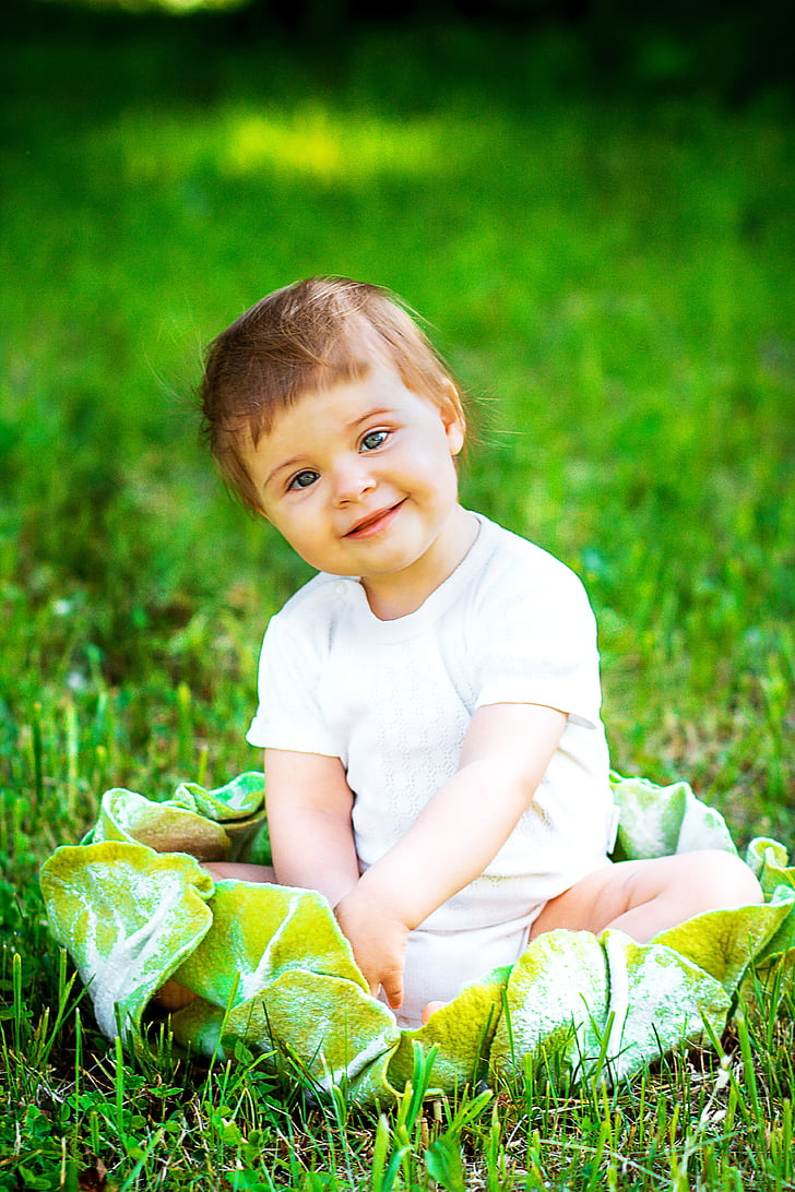 smiling baby sitting on green grass