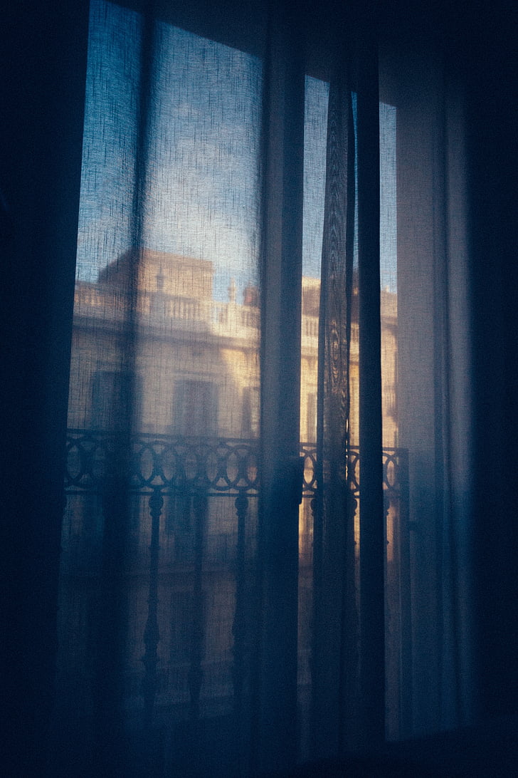 photo of window with blue shear window curtain
