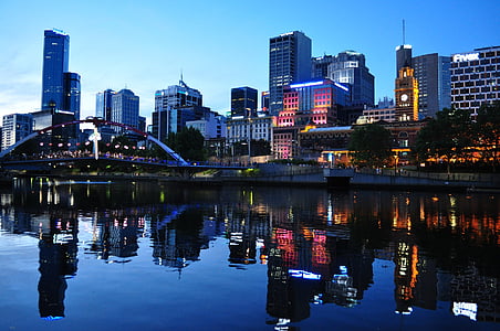 high-rise buildings reflected on calm body of water at dusk