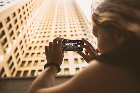 woman holding smartphone taking photo of the high-rise building
