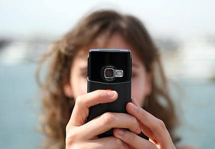 selective focus photography of woman holding phone