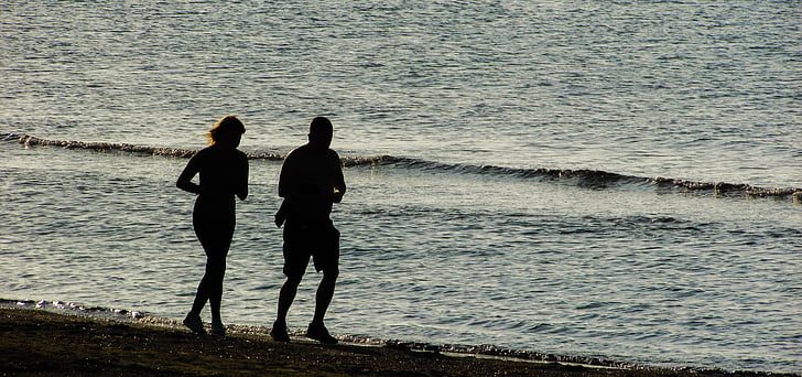 silhouette of two person running on seashore