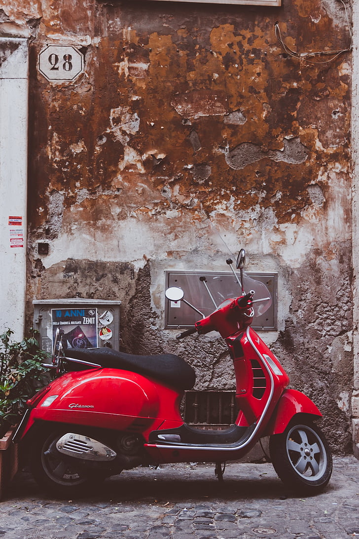 red motor scooter parked near wall