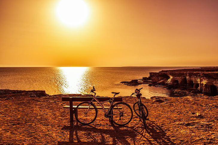 two bicycle beside bench during sunset