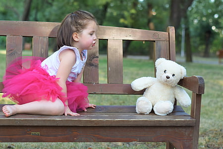 photo of girl sitting near white bear plush toy