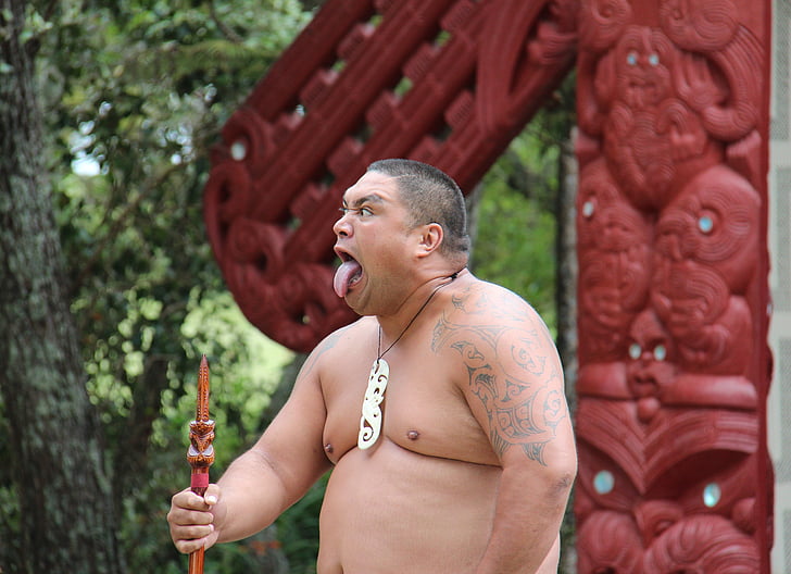 man showing his tongue and holding a stick during daytime