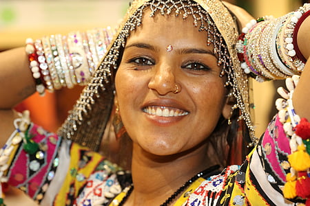 woman wearing gold scarf and yellow, black, pink, and green top