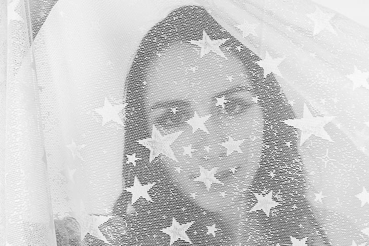 grayscale photography of woman's face covered with star print textile