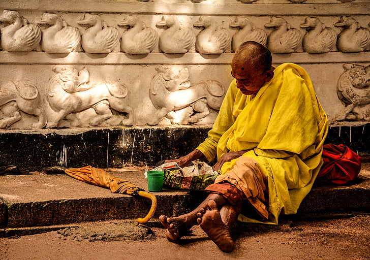 monk sitting near brown umbrella