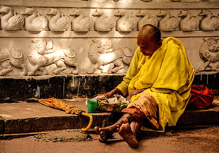 monk sitting near brown umbrella
