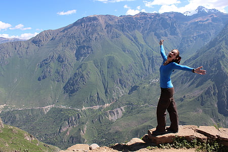 woman in blue shirt and black pants on mountain during daytime