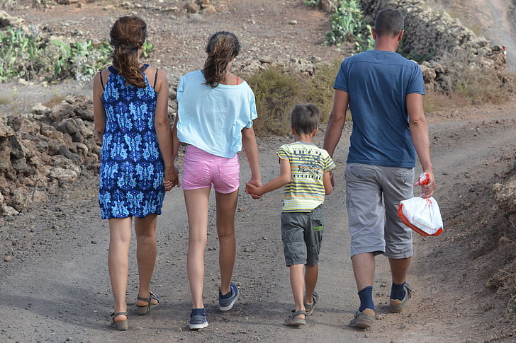 woman, girl, boy, and man holding hands together