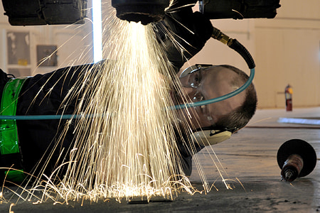 photography of man wearing earmuffs welding