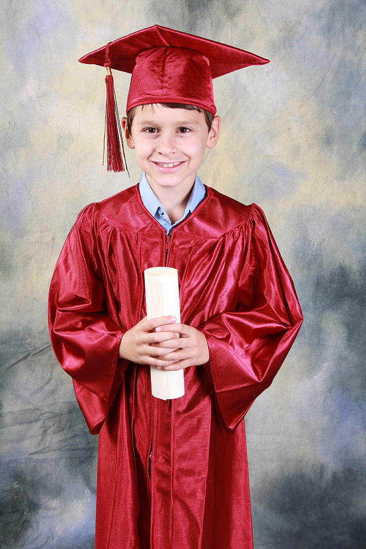 smiling boy wearing red academic dress holding diploma
