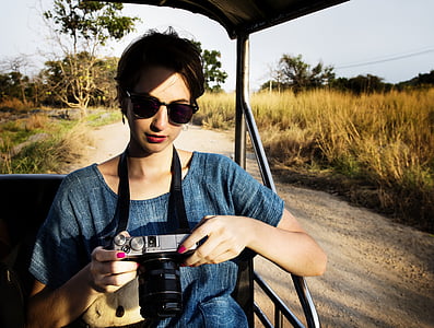 woman wearing blue top sitting on vehicle seat while holding DSLR camera