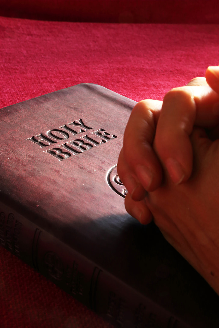 person's hands on Holy Bible