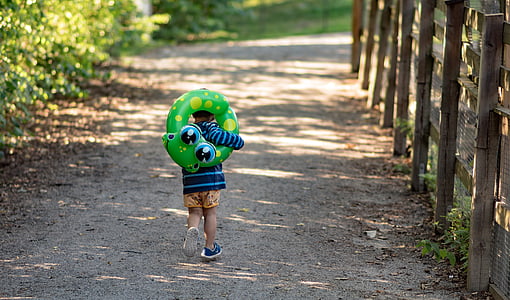 toddler carrying green inflatable floating rin