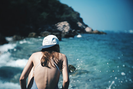 woman wearing white fitted cap near sea at daytime