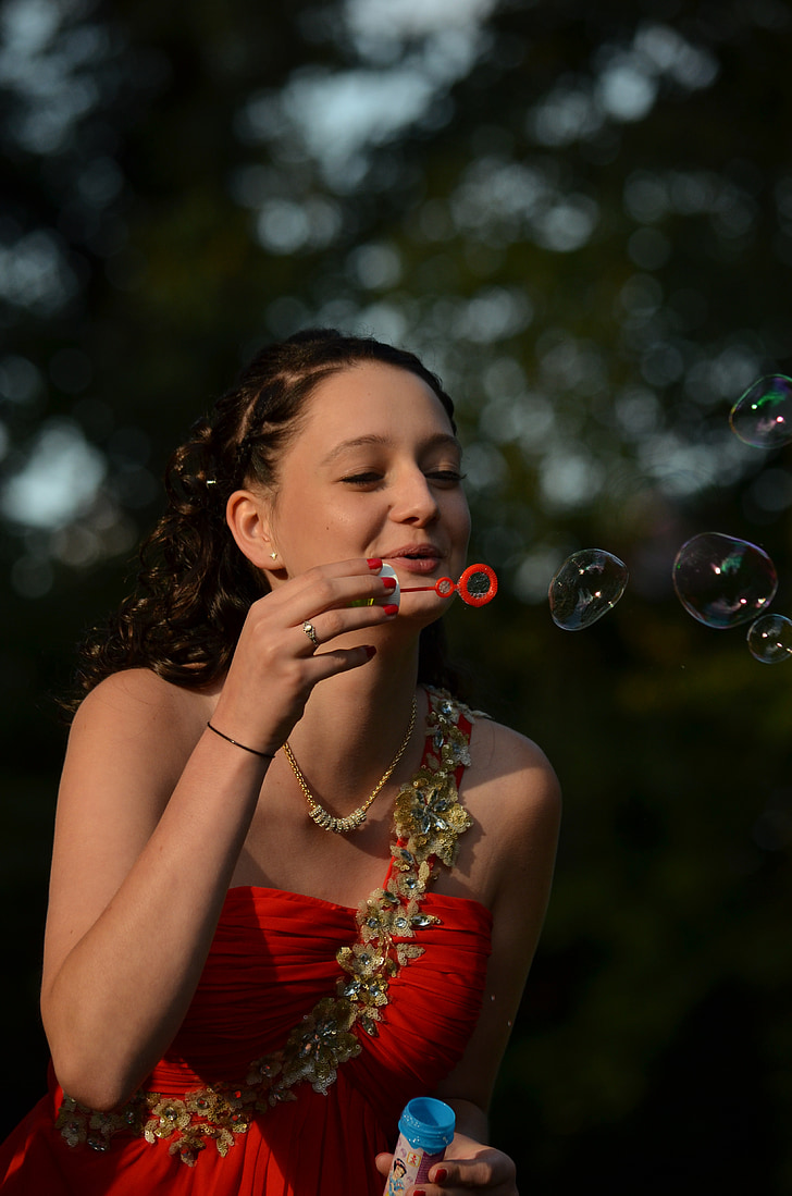 woman in red dress blowing bubbles