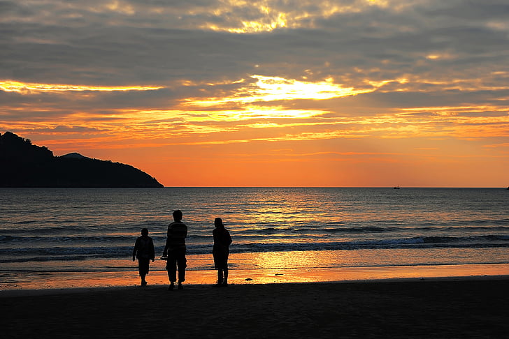 silhouette of three people near in the beach