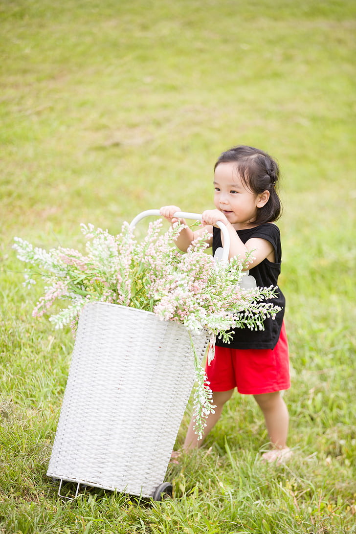 girl wearing black sleeveless shirt holding basket of flowers