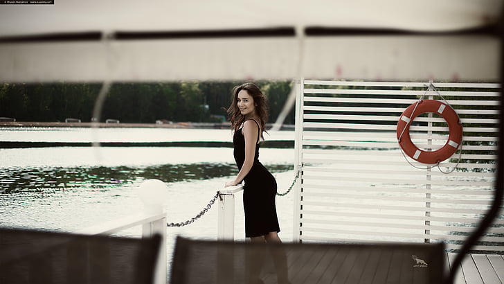 woman wearing black sleeveless dress near body of water