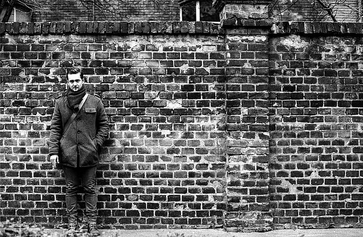 man leaning on bricked wall