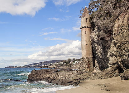 brown concrete lighthouse near body of water under blue and white sky