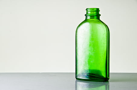 green glass bottle on top of gray surface
