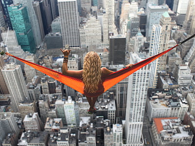 woman on orange hammock on top of high-rise building