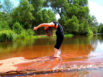 woman standing on ground bending her body surrounded by body of water