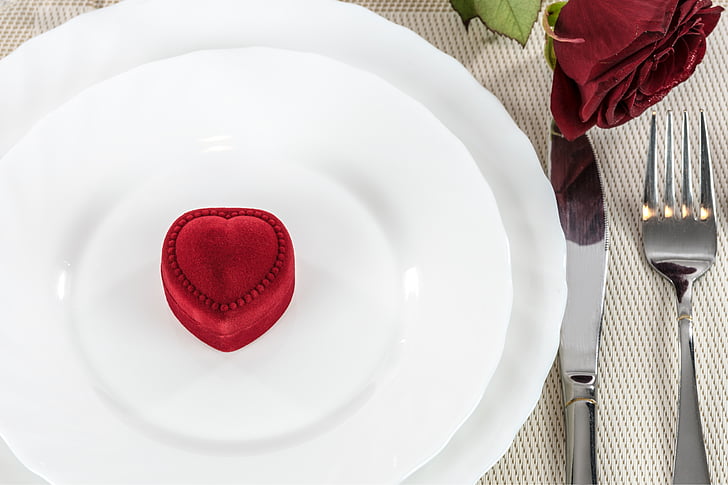 heart-shaped red suede ring box on round white plate