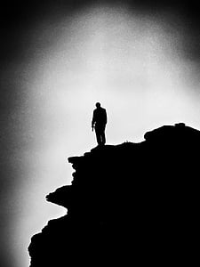 grayscale photo of a man on the top of mountain
