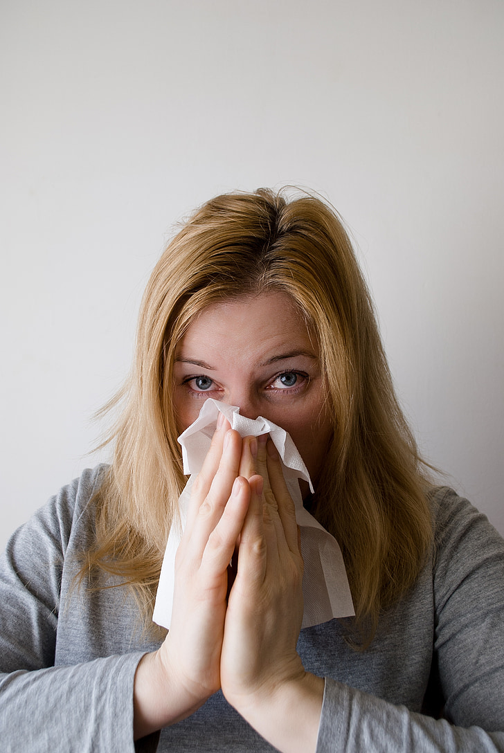 woman sneezing on white tissue paper