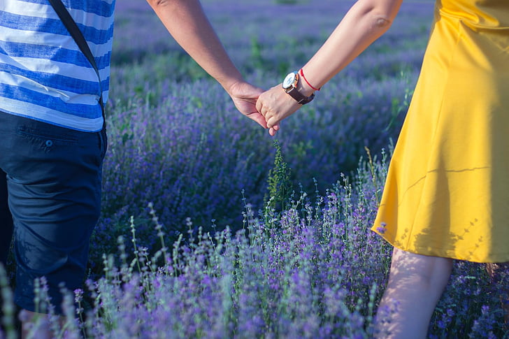 man and woman holding hands standing in lavender fields