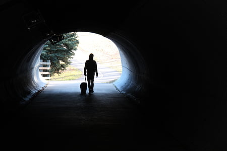 silhouette of person walking inside tunnel at daytime